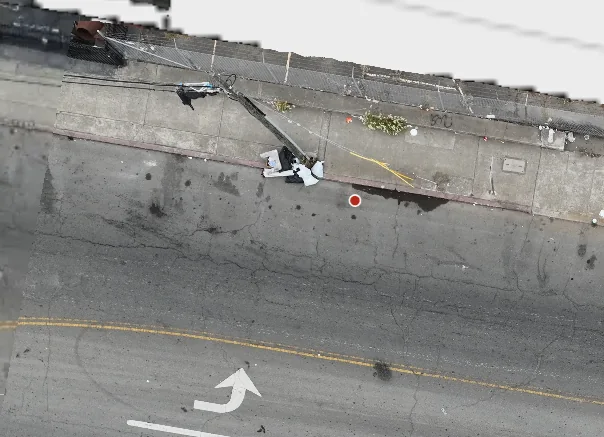 Aerial view of a street corner with a pile of dumped material beside a leaning utility pole