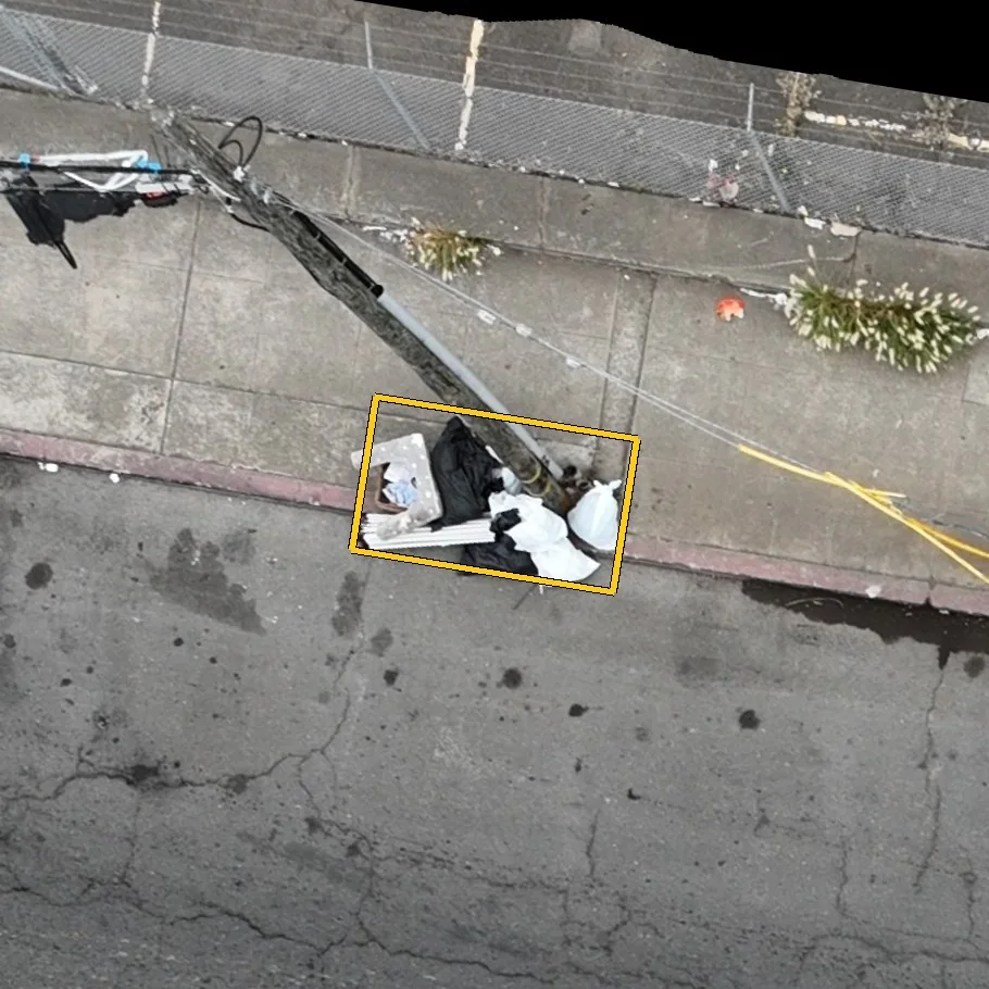 Close aerial view of the pile at the pole base with a yellow bounding box drawn around it by the detection model