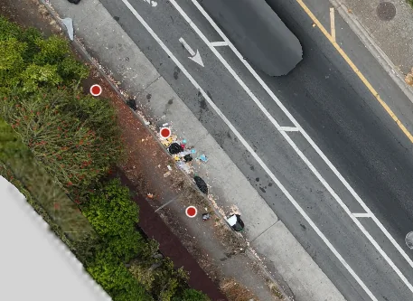 The same sidewalk two flights later, now with a large pile of bagged and loose garbage along the curb, marked with red detection circles