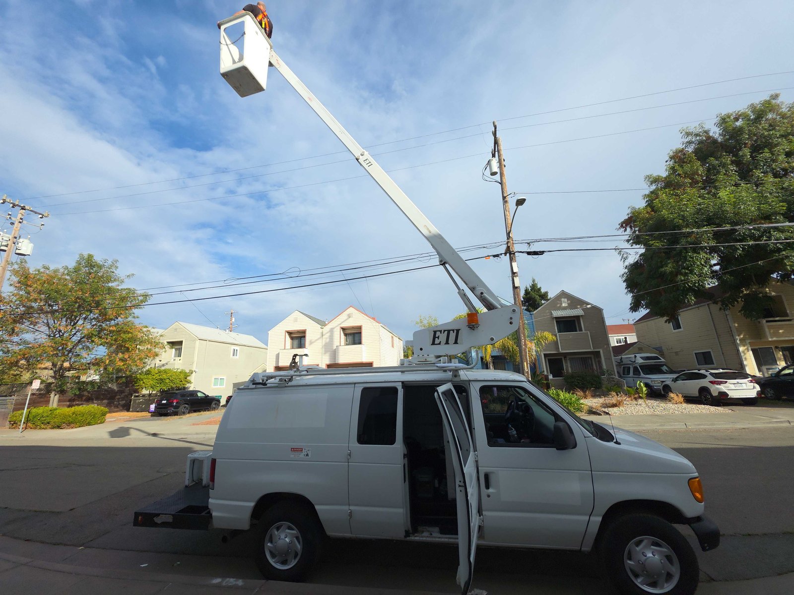 Aerbits field operations van with a raised bucket lift at a street-side utility pole