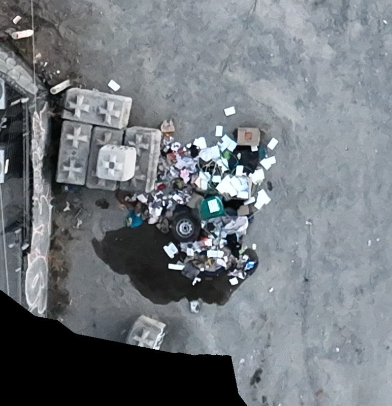 Aerial view of an illegal dumping pile beside a concrete barrier