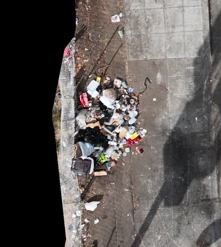 Aerial view of an illegal dumping pile against a chain-link fence