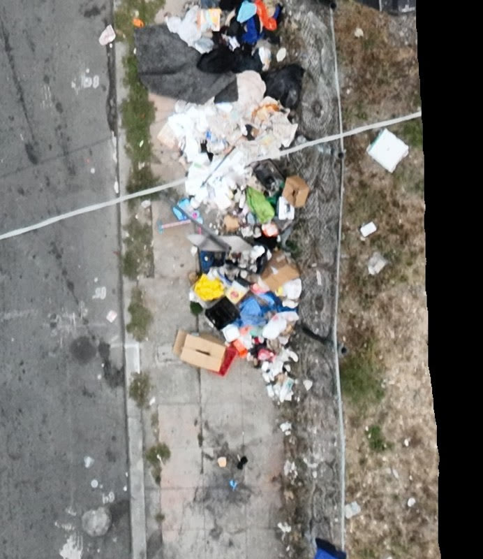 Aerial view of a long illegal dumping pile along a fence line